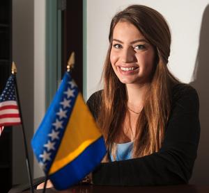 Medina Spiodic, a native of Bosnia who is a student at the University of Illinois, sits near a U.S. flag and Bosnian flag, at the International Studies Building in Champaign on Friday, Sept. 27, 2013.